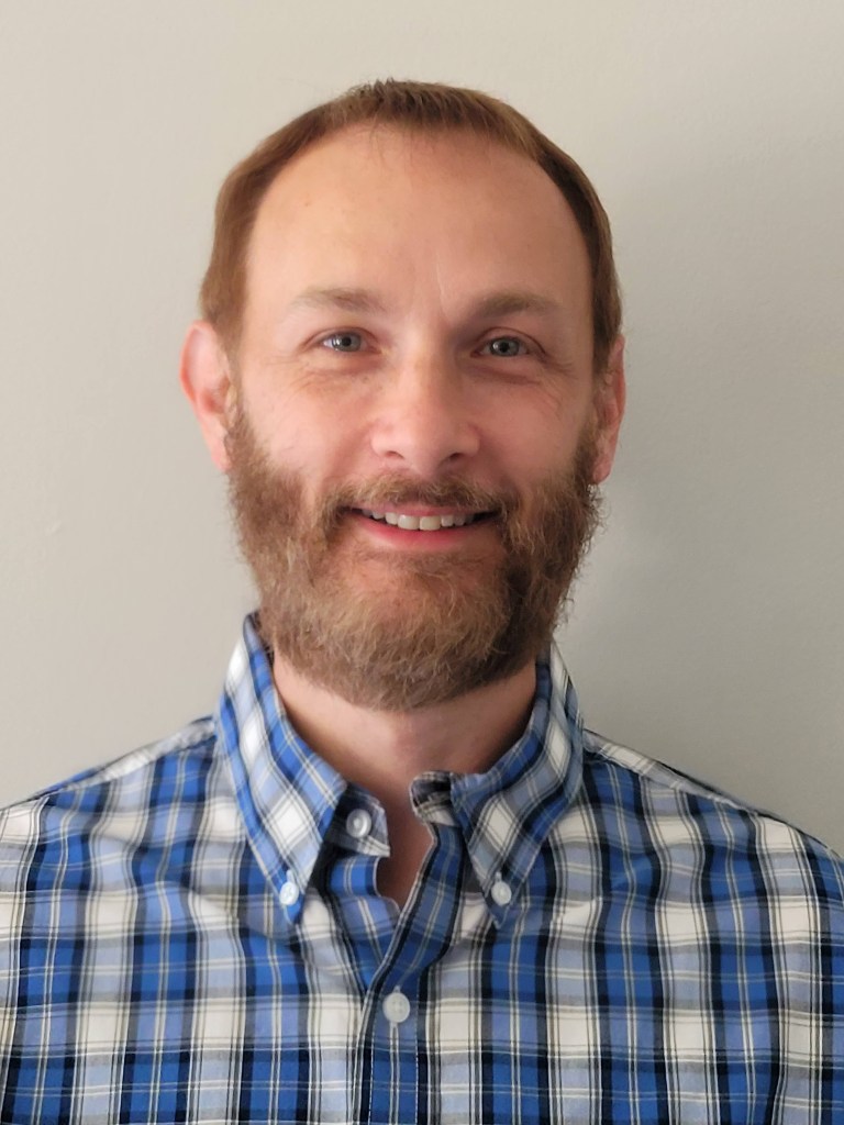 Headshot of co-owner Robert Harris, smiling in a blue and white button down shirt.